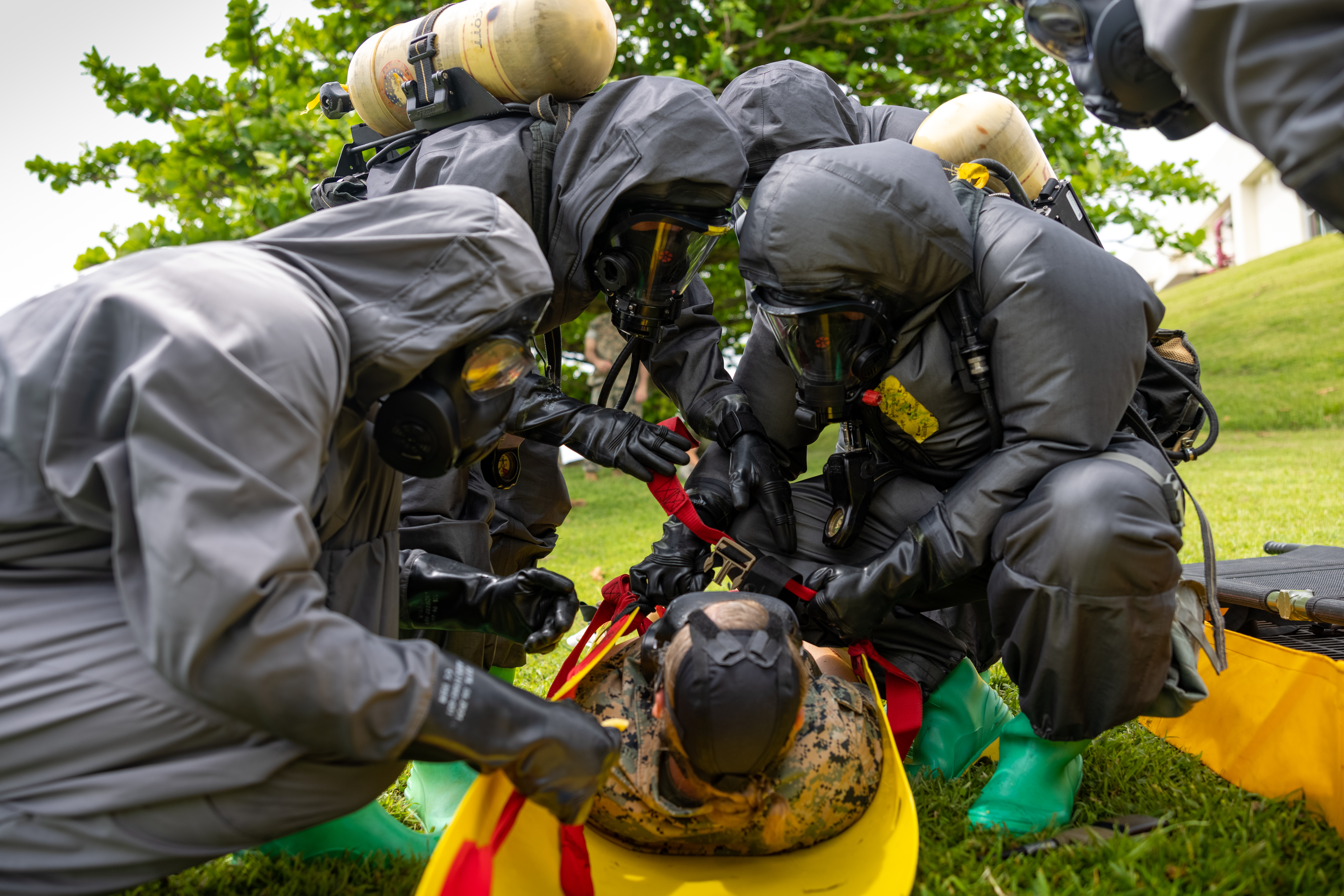 U.S. Marines provide aid to a simulated casualty during a Chemical, Biological, Radiological, and Nuclear (CBRN) defense site control training exercise on Camp Courtney, Okinawa, Japan, Sept. 8, 2023. CBRN defense specialists are responsible for conducting chemical detection and identification, biological agent collection, decontamination procedures, and first aid for unit personnel. The Marines are with Headquarters Battalion, 3d Marine Division.